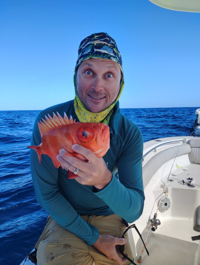 Angler holding a vermilion snapper caught jigging offshore from Pensacola